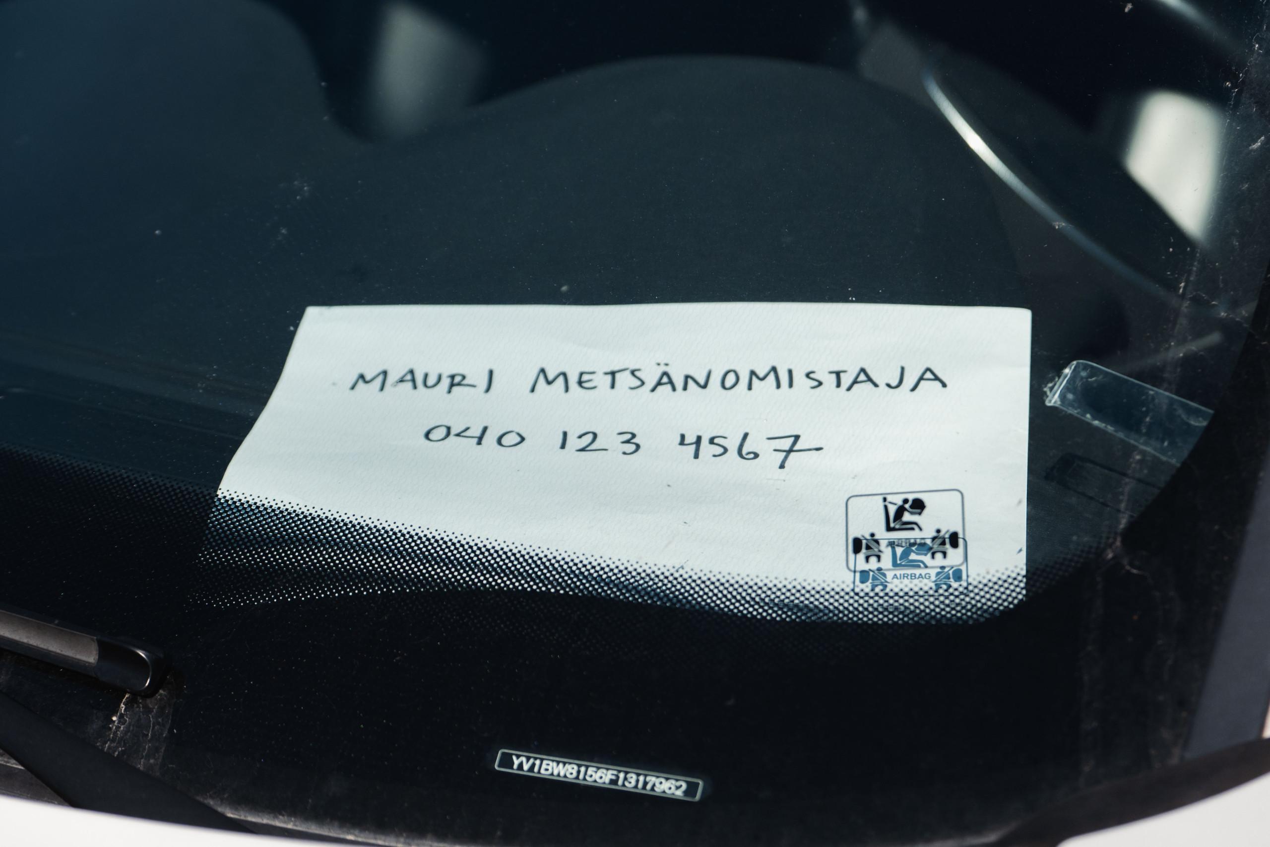 auton kojelaudalla lappu, jossa lukee nimi ja puhelinnumero