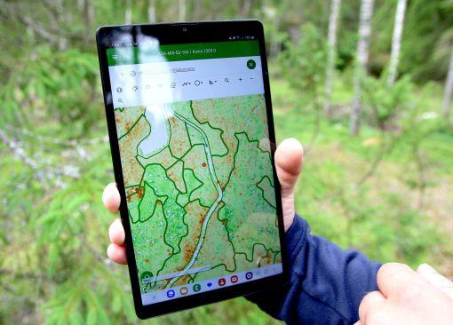 ForestKIT-sovellus esillä tabletissa henkilön kädessä metsässä