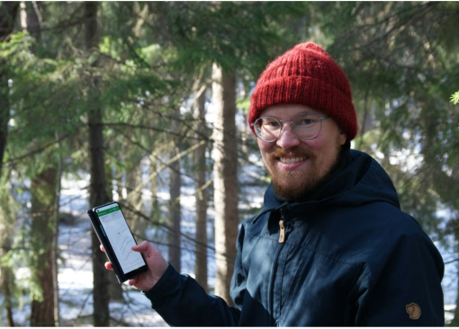 Petri Latva-Käyrä puhelin kädessään talvisessa metsässä